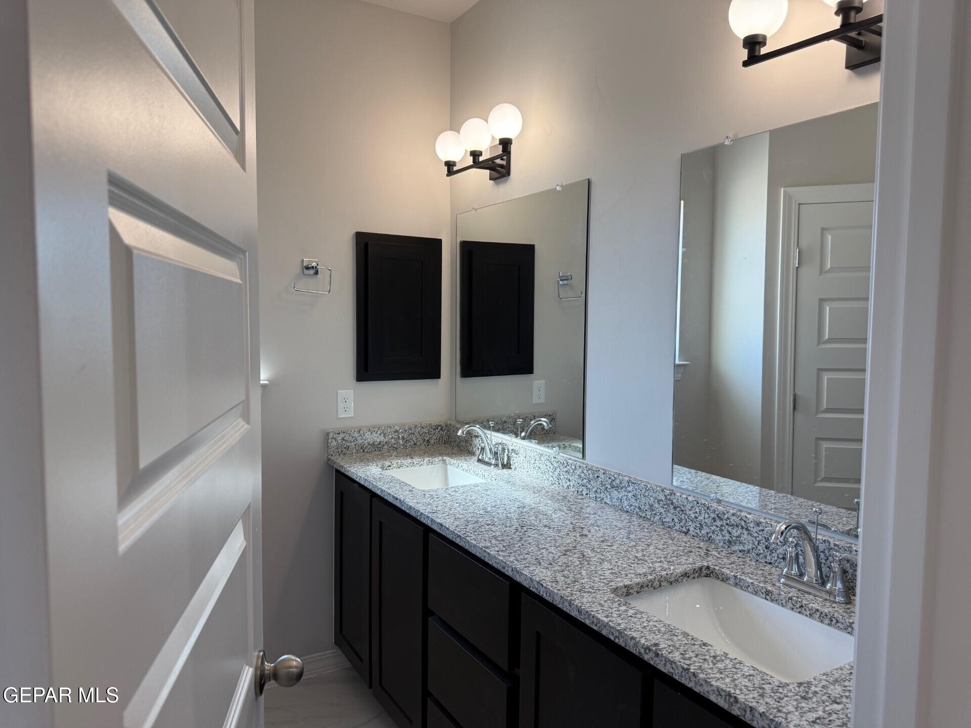 7703 California Stage Street Vinton, TX 79821 - Photo 11 of 14 a bathroom with a granite countertop sink a large mirror and a shower
