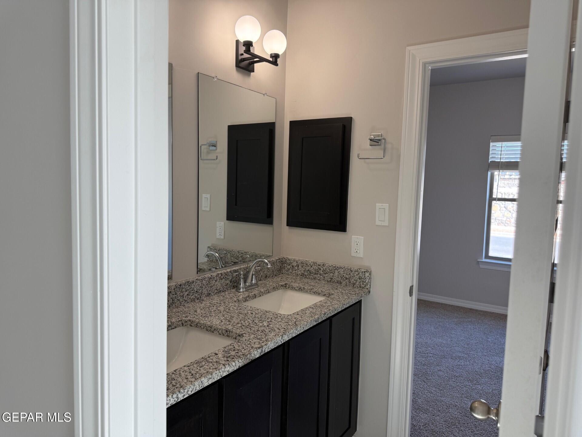 7703 California Stage Street Vinton, TX 79821 - Photo 4 of 14 a bathroom with a granite countertop sink and a mirror