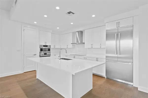 a kitchen with kitchen island a sink stainless steel appliances and cabinets