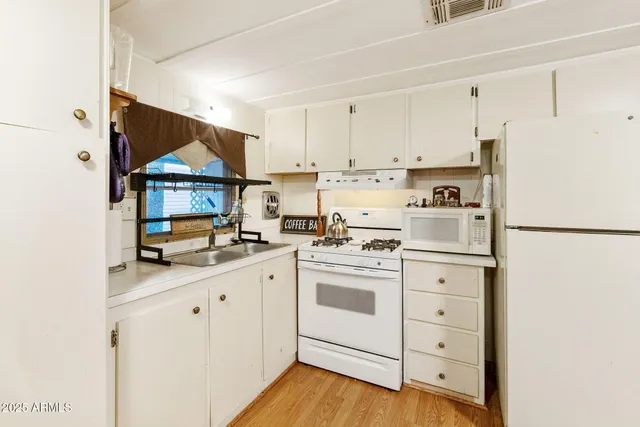 a kitchen with stainless steel appliances granite countertop a sink a stove a refrigerator and white cabinets