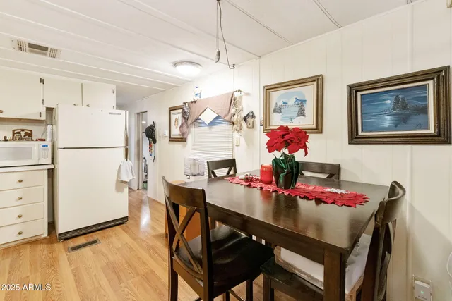a view of a dining room with furniture refrigerator and wooden floor