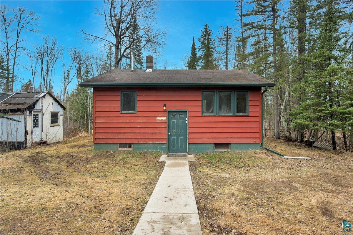 View of front facade featuring a front lawn, a chimney, and an outdoor structure