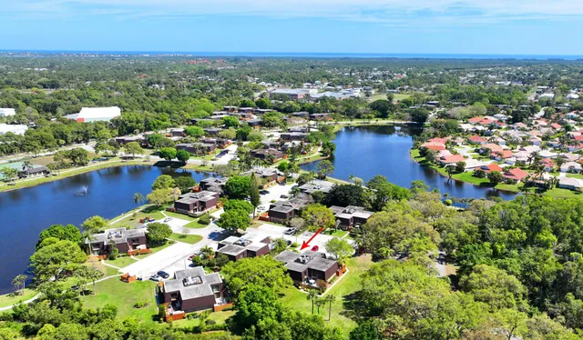 an aerial view of a houses with a lake and trees all around