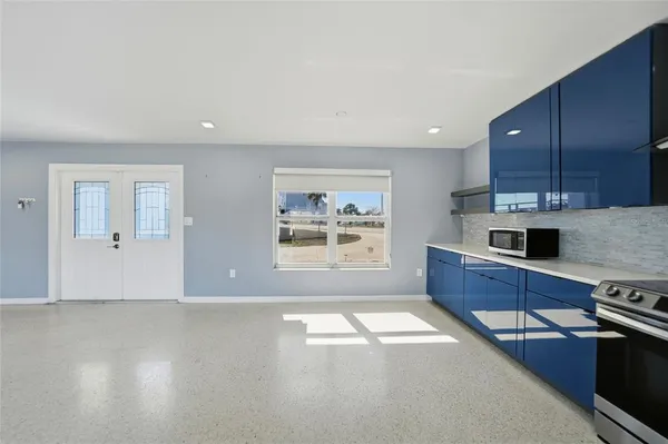 a large kitchen with stainless steel appliances a stove a sink a refrigerator wooden floor and cabinets