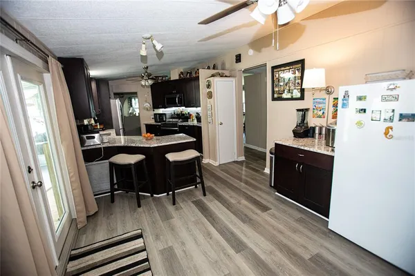 a kitchen with a refrigerator a sink dishwasher a dining table and chairs with wooden floor