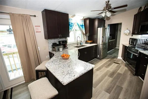a kitchen with stainless steel appliances granite countertop sink stove refrigerator and wooden floor