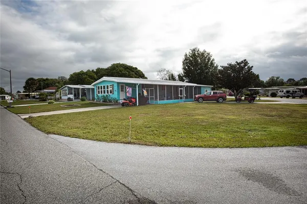 a view of a house with a big yard and large trees