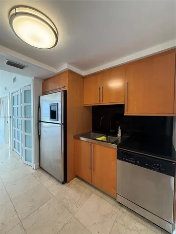 a view of kitchen and empty room with wooden floor