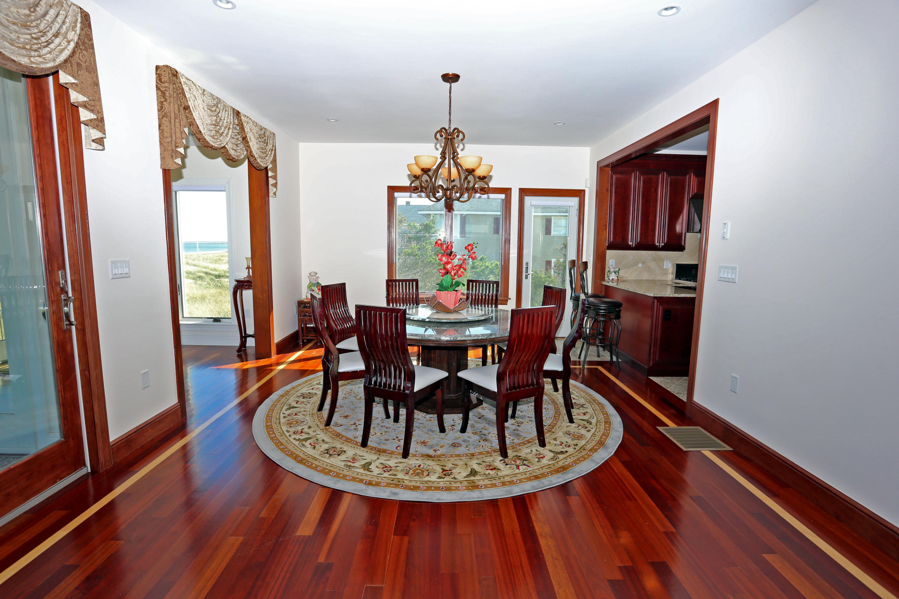 99 Phillips Road Sagamore Beach, MA 02562 - Photo 14 of 30 a dining room with wooden floor a chandelier a glass table and chairs