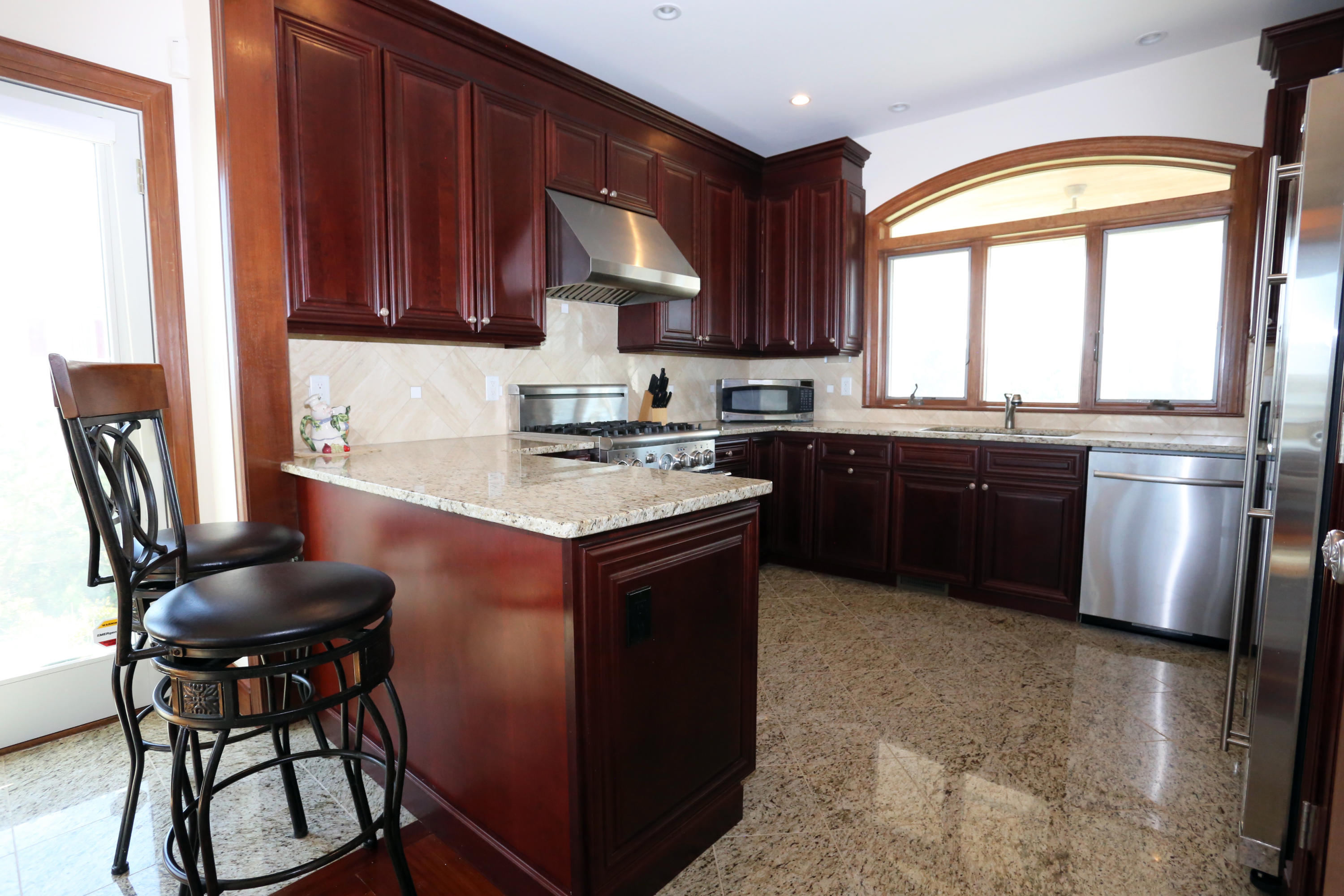 99 Phillips Road Sagamore Beach, MA 02562 - Photo 16 of 30 a kitchen with stainless steel appliances granite countertop wooden cabinets a sink a stove a refrigerator and island with wooden floor