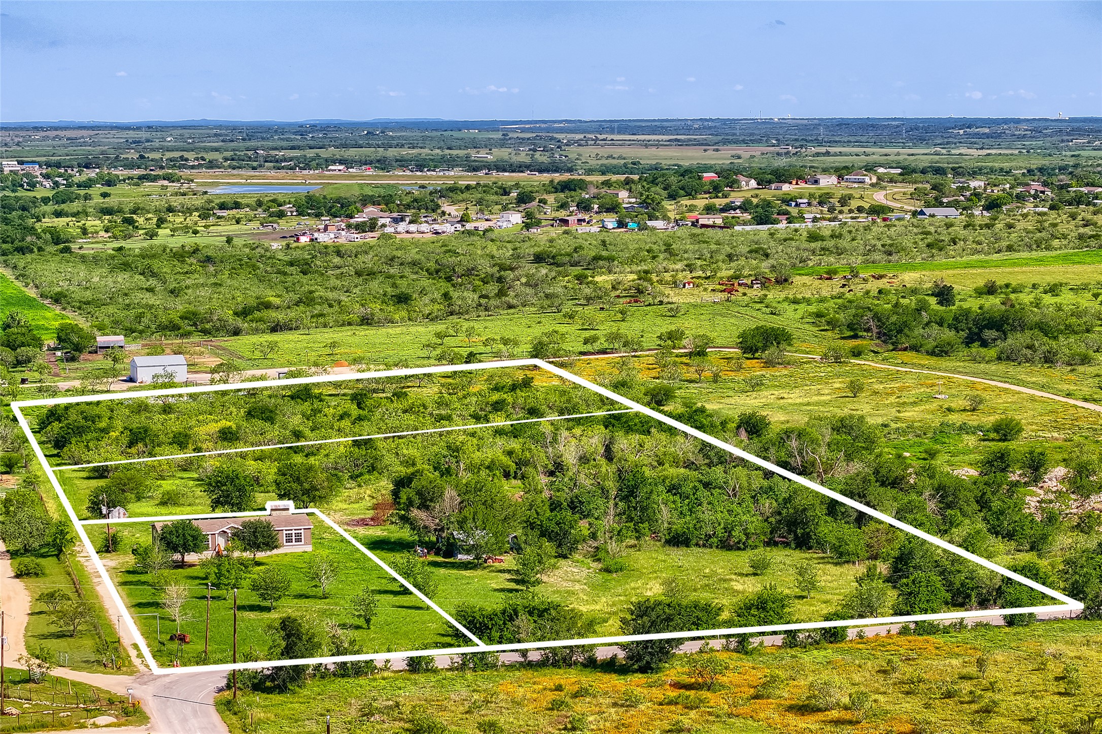 401 Graef Road Kyle, TX 78640 - Photo 6 of 30 A sweeping aerial view reveals a private dwelling nestled amidst verdant fields, bordered by a tranquil road.