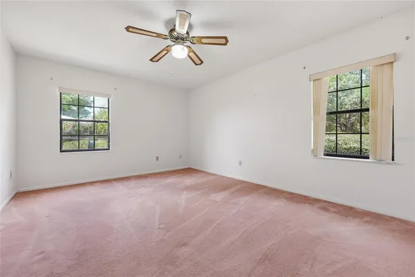 an empty room with windows and ceiling fan