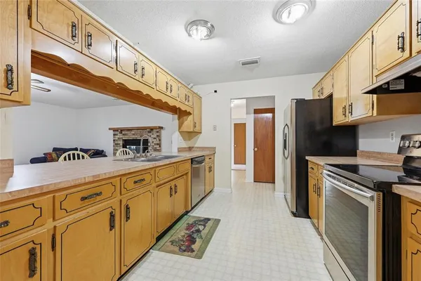 a kitchen with stainless steel appliances granite countertop a refrigerator a stove and a sink