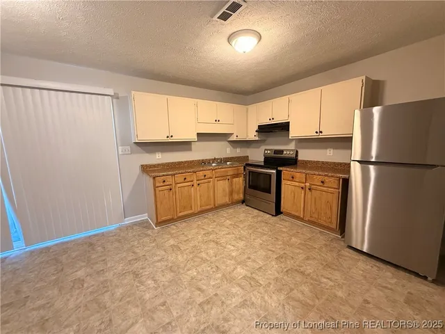 a kitchen with stainless steel appliances granite countertop a refrigerator a stove a sink dishwasher and a refrigerator