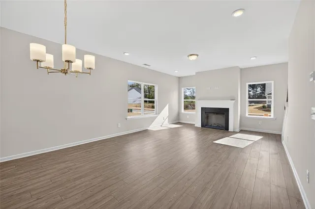 an empty room with wooden floor fireplace and windows