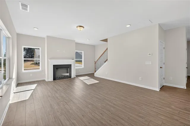 an empty room with wooden floor fireplace and windows