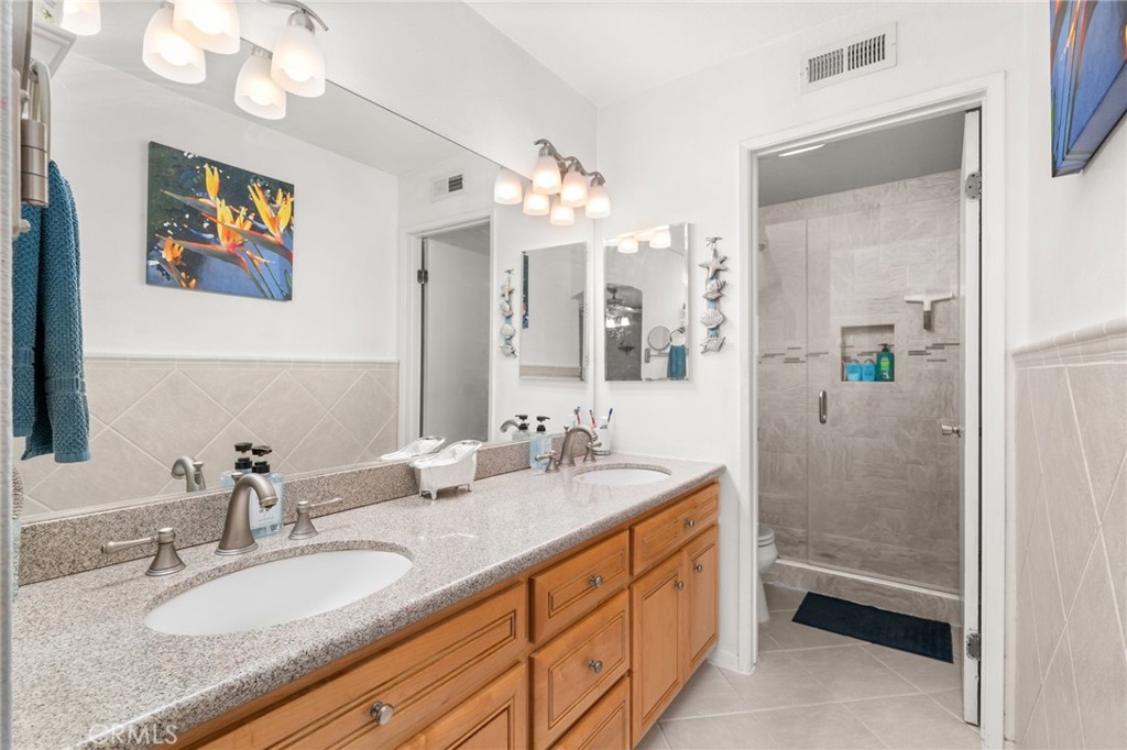 8576 Creekside Place Rancho Cucamonga, CA 91730 - Photo 20 of 37 a bathroom with a granite countertop double vanity sink a mirror a shower and a