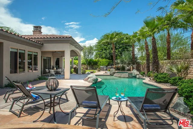 a view of a patio with table and chairs potted plants and palm tree