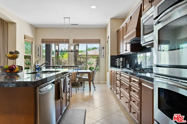 a kitchen with stainless steel appliances granite countertop a stove top oven a sink a dining table and chairs