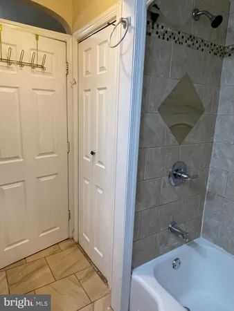 a bathroom with a tub a mirror and a shower