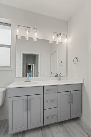 a bathroom with a double vanity sink and a mirror with window