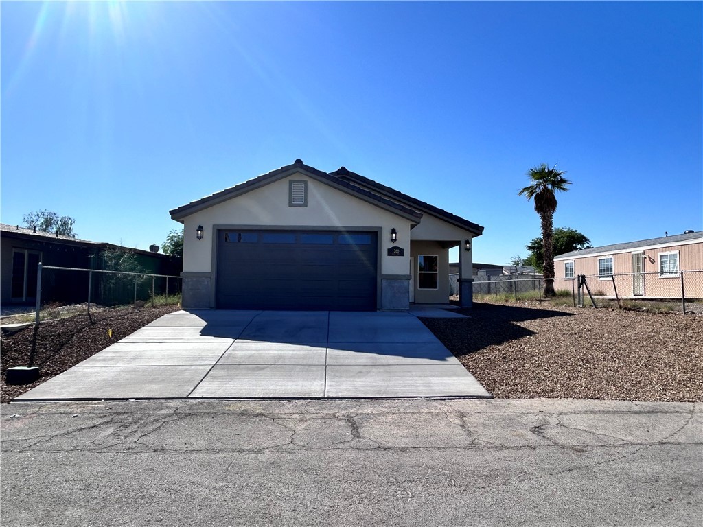 1266 Wilson Road Bullhead City, AZ 86442 - Photo 1 of 29 View of front of property with concrete driveway, stucco siding, and a garage