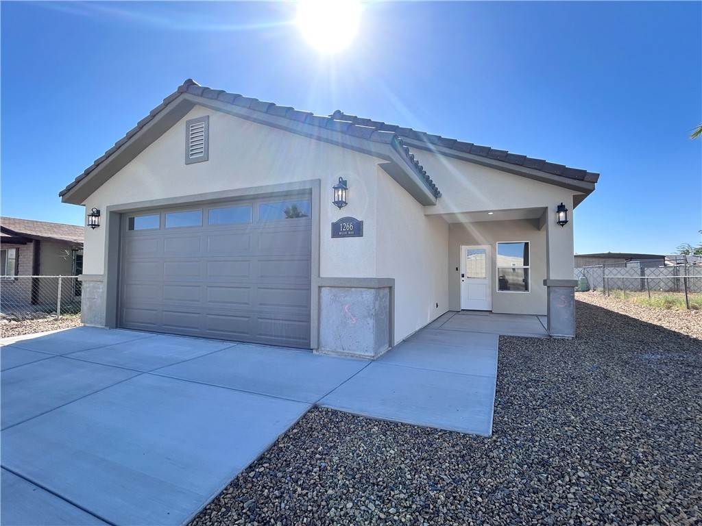 1266 Wilson Road Bullhead City, AZ 86442 - Photo 4 of 29 Ranch-style home with driveway, a tiled roof, stucco siding, and an attached garage