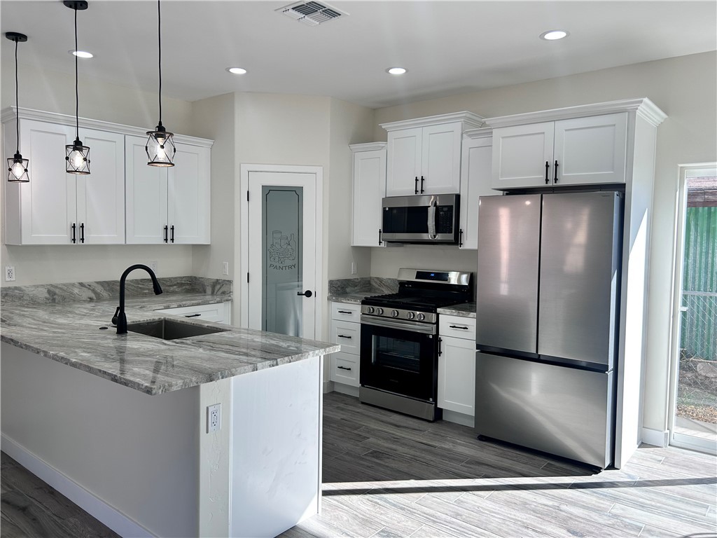 1266 Wilson Road Bullhead City, AZ 86442 - Photo 6 of 29 Kitchen featuring appliances with stainless steel finishes, light stone countertops, white cabinets, a peninsula, and dark wood finished floors