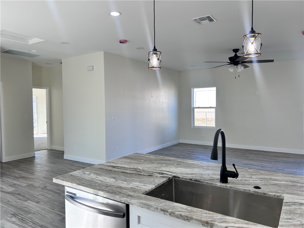 1266 Wilson Road Bullhead City, AZ 86442 - Photo 29 of 29 Kitchen with open floor plan, hanging light fixtures, dark wood-style flooring, light stone counters, and stainless steel dishwasher