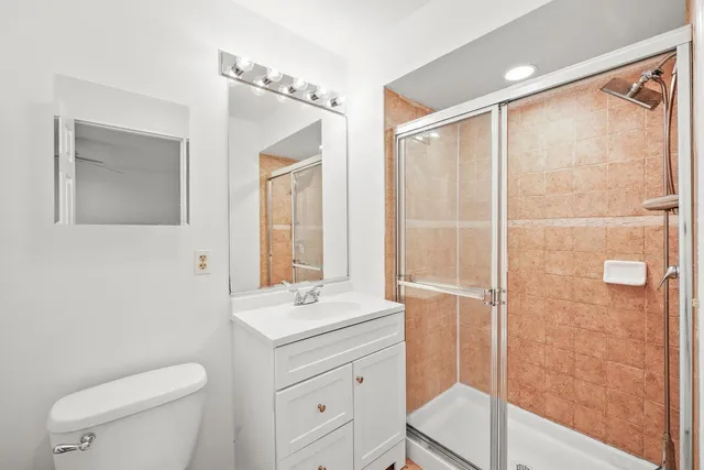 a bathroom with a toilet a sink a mirror a shower and vanity