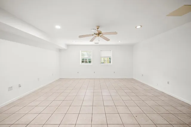 an empty room with windows and chandelier fan