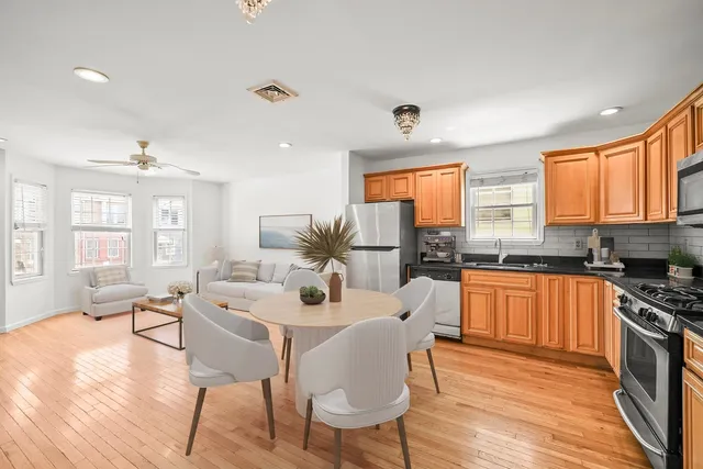 a kitchen with stainless steel appliances granite countertop a stove top oven a sink dishwasher a dining table and chairs with wooden floor