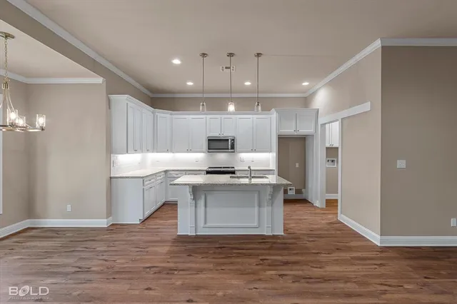 a kitchen with stainless steel appliances a stove top oven a sink dishwasher a refrigerator and a dining table with wooden floor