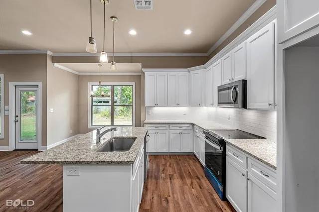 a kitchen with granite countertop stainless steel appliances sink stove and wooden floor