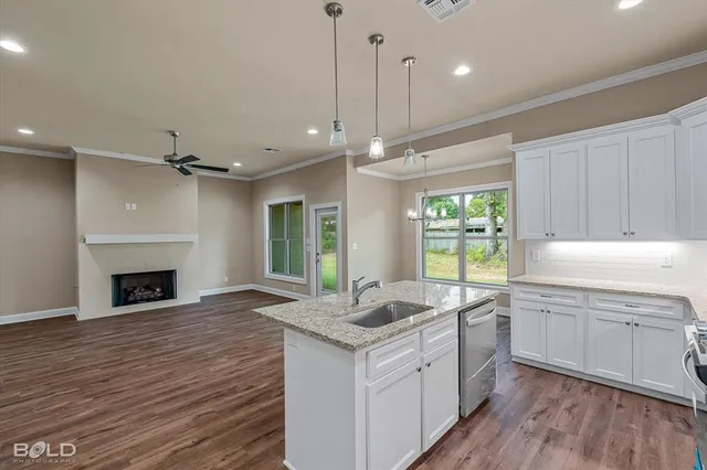 a kitchen with granite countertop a sink cabinets and wooden floor