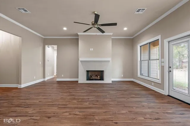 a view of an empty room with wooden floor fireplace and a window