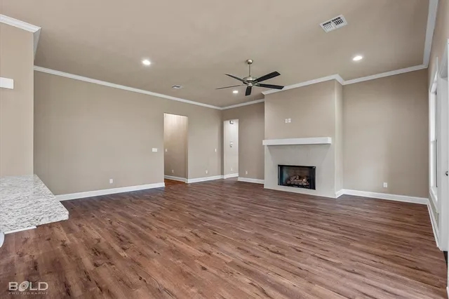 a view of an empty room with wooden floor and a fireplace