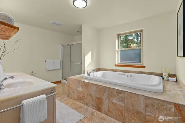 a spacious bathroom with a tub sink and mirror
