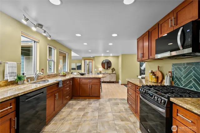 a kitchen with stainless steel appliances granite countertop a stove a sink and a microwave
