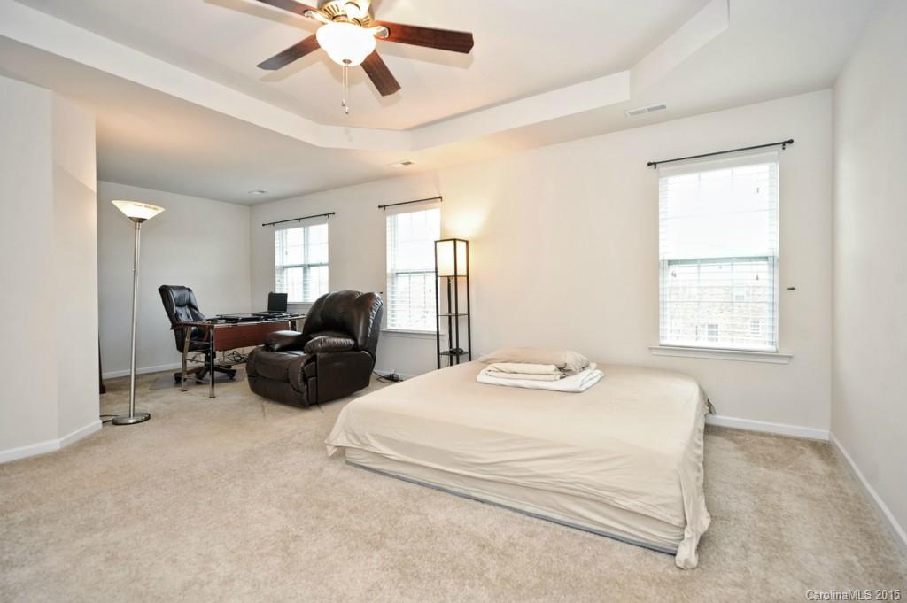 9927 Paxton Run Road Charlotte, NC 28277 - Photo 14 of 24 a spacious bedroom with a bed a couch and a ceiling fan