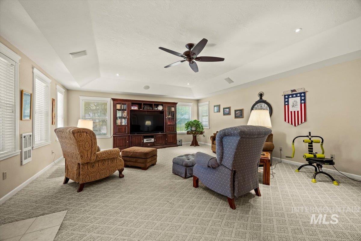 7425 Robinson Road Kuna, ID 83634 - Photo 17 of 50 Living room with a tray ceiling, light carpet, a ceiling fan, and healthy amount of natural light