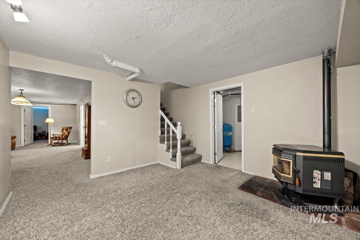 7425 Robinson Road Kuna, ID 83634 - Photo 36 of 50 Living area with a wood stove, stairs, carpet flooring, and a textured ceiling