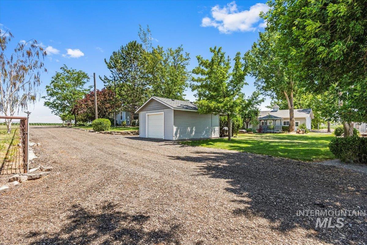 7425 Robinson Road Kuna, ID 83634 - Photo 50 of 50 View of grassy yard featuring a garage, an outbuilding, and dirt driveway