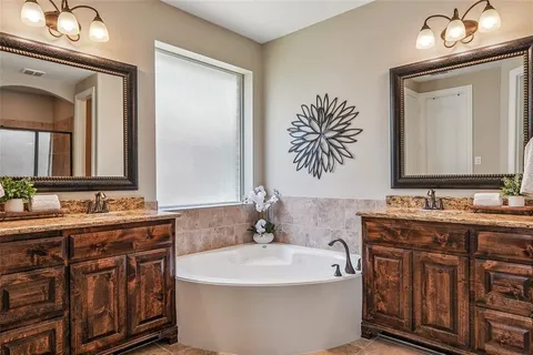 a bathroom with a bathtub a double vanity sink and a mirror