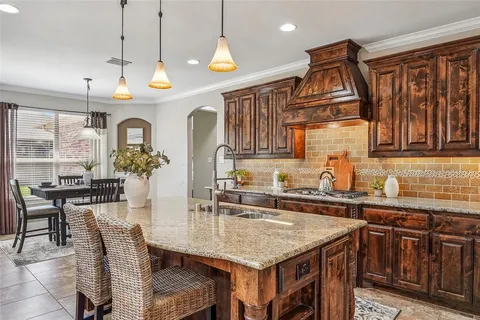 a kitchen with granite countertop a stove a sink a dining table and chairs