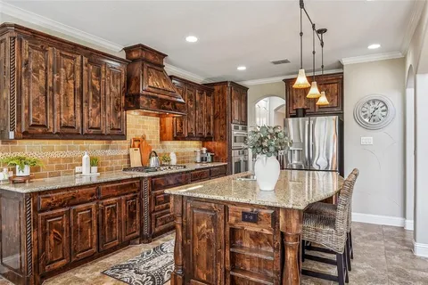 a kitchen with stainless steel appliances granite countertop a kitchen island a stove a sink dishwasher and cabinets with wooden floor