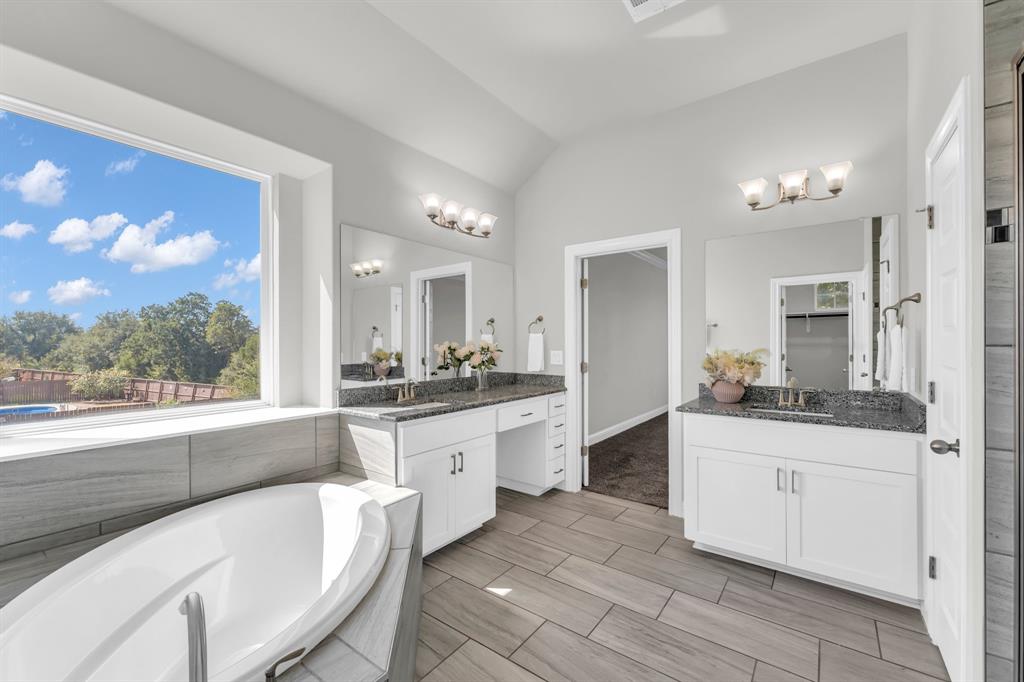 110 Magona Trail Georgetown, TX 78628 - Photo 33 of 38 A spacious primary bathroom boasts a luxurious soaking tub, dual vanities, and expansive window views.