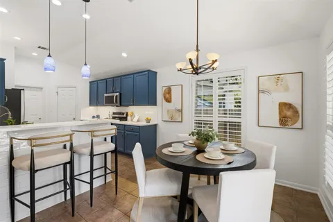 a kitchen with a dining table chairs and white cabinets with wooden floor
