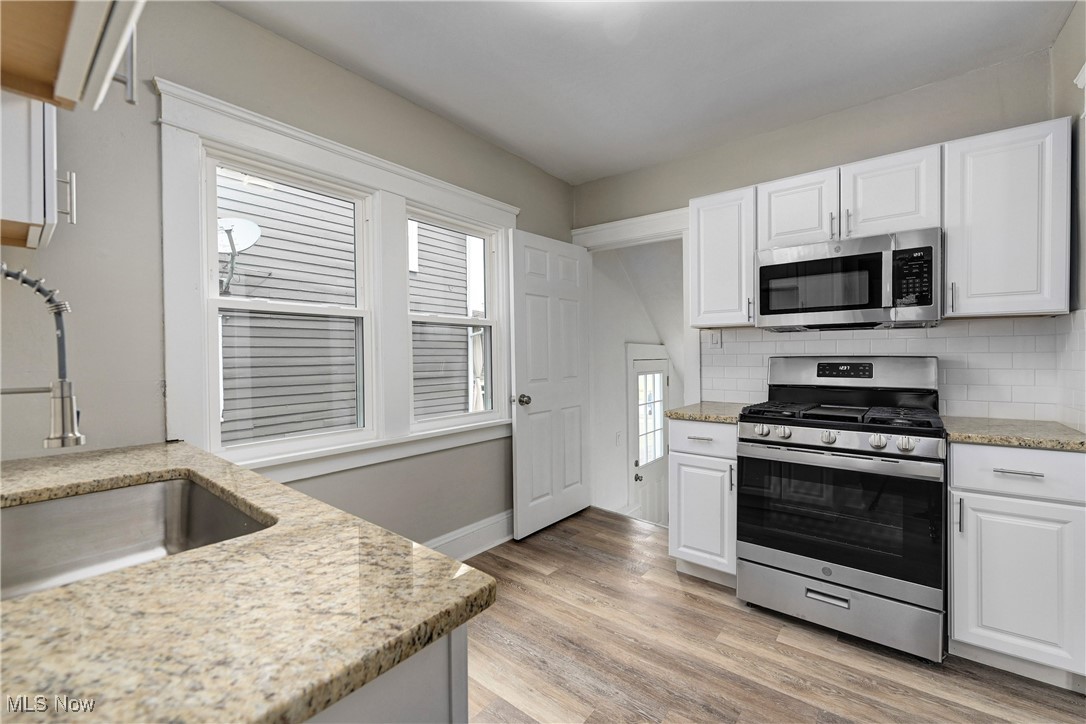 896 Selwyn Road Cleveland Heights, OH 44112 - Photo 10 of 23 Kitchen featuring appliances with stainless steel finishes, white cabinets, decorative backsplash, and light wood-style flooring