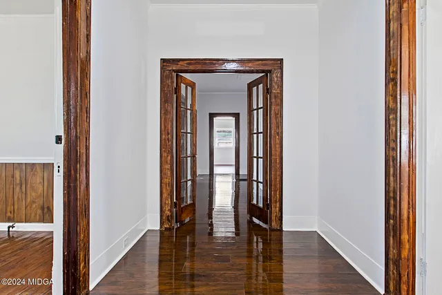 a hallway with wooden floor windows and front door